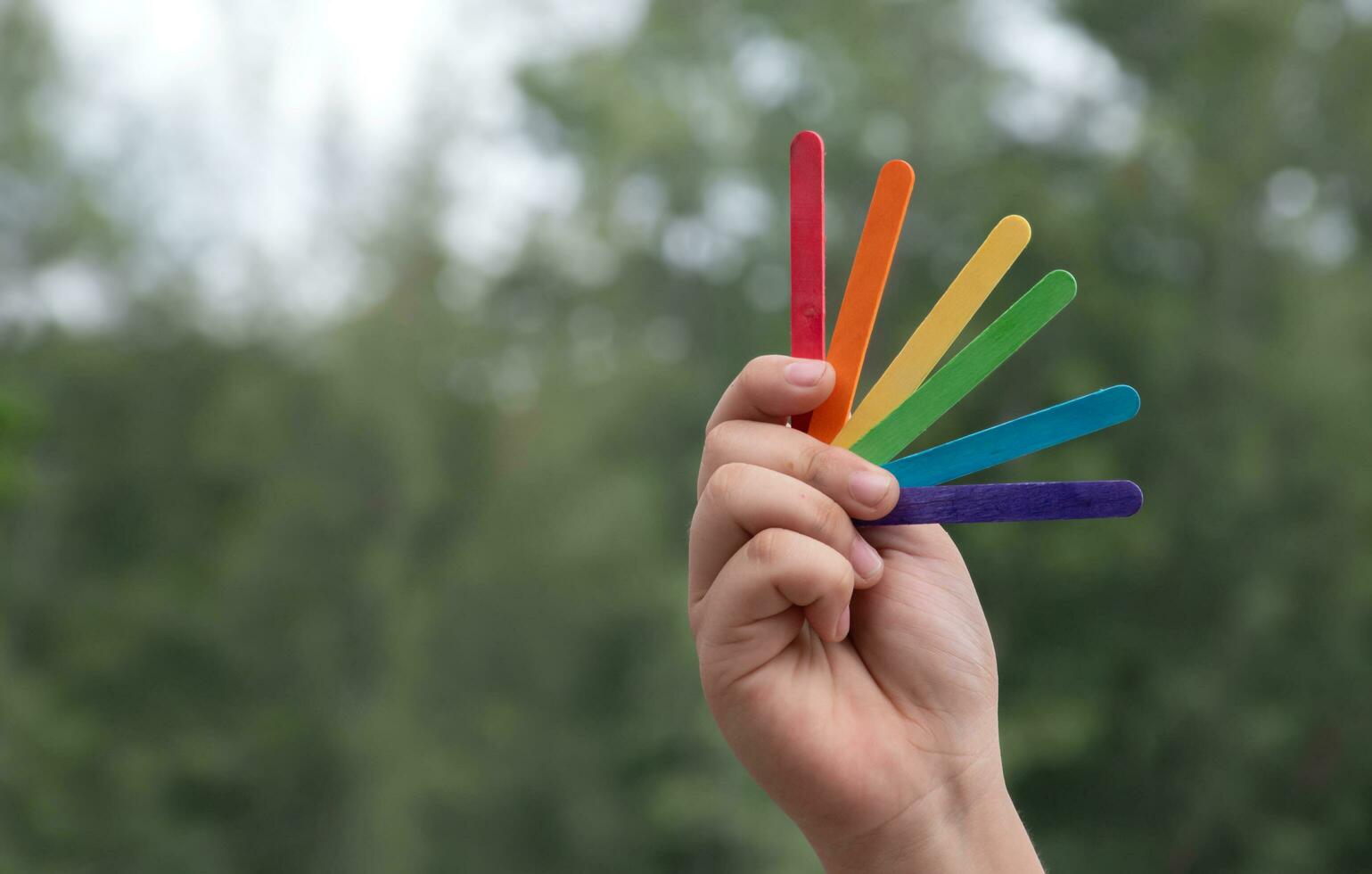 Ice-cream sticks in rainbow colours holding in hands of asian boy, soft and selective focus, concept for calling out all people to support LGBT events and campaigns around the world. photo