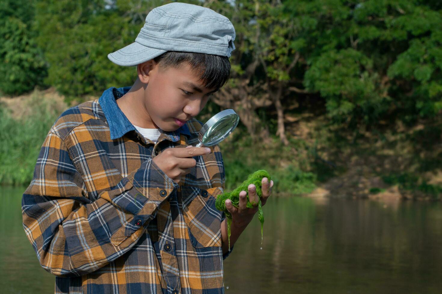 Freshwater algae study of asian boy in the local river nearby, global warming and climate change study concept. photo