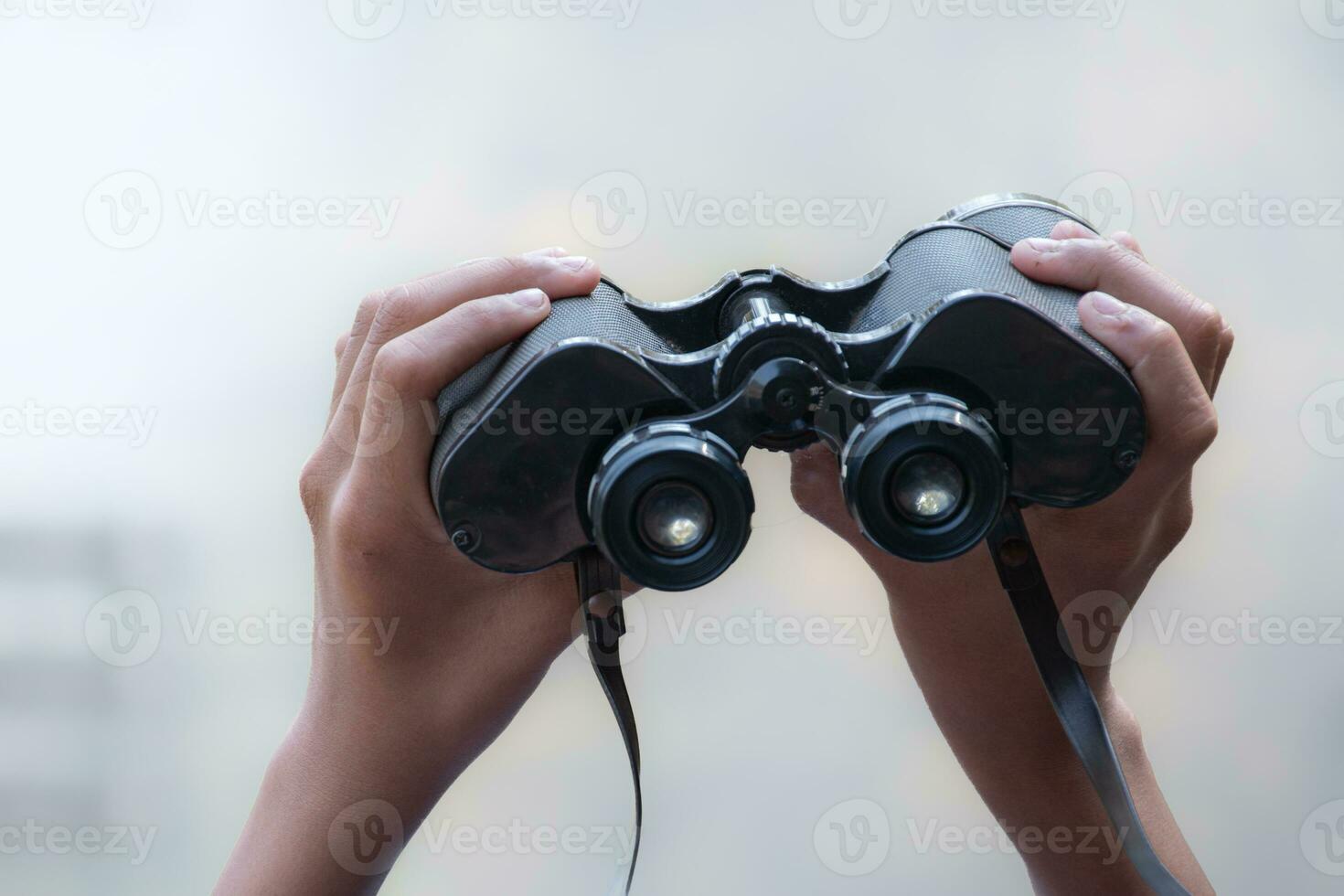 Binoculars holding in hands against foggy background, clipping paths. photo