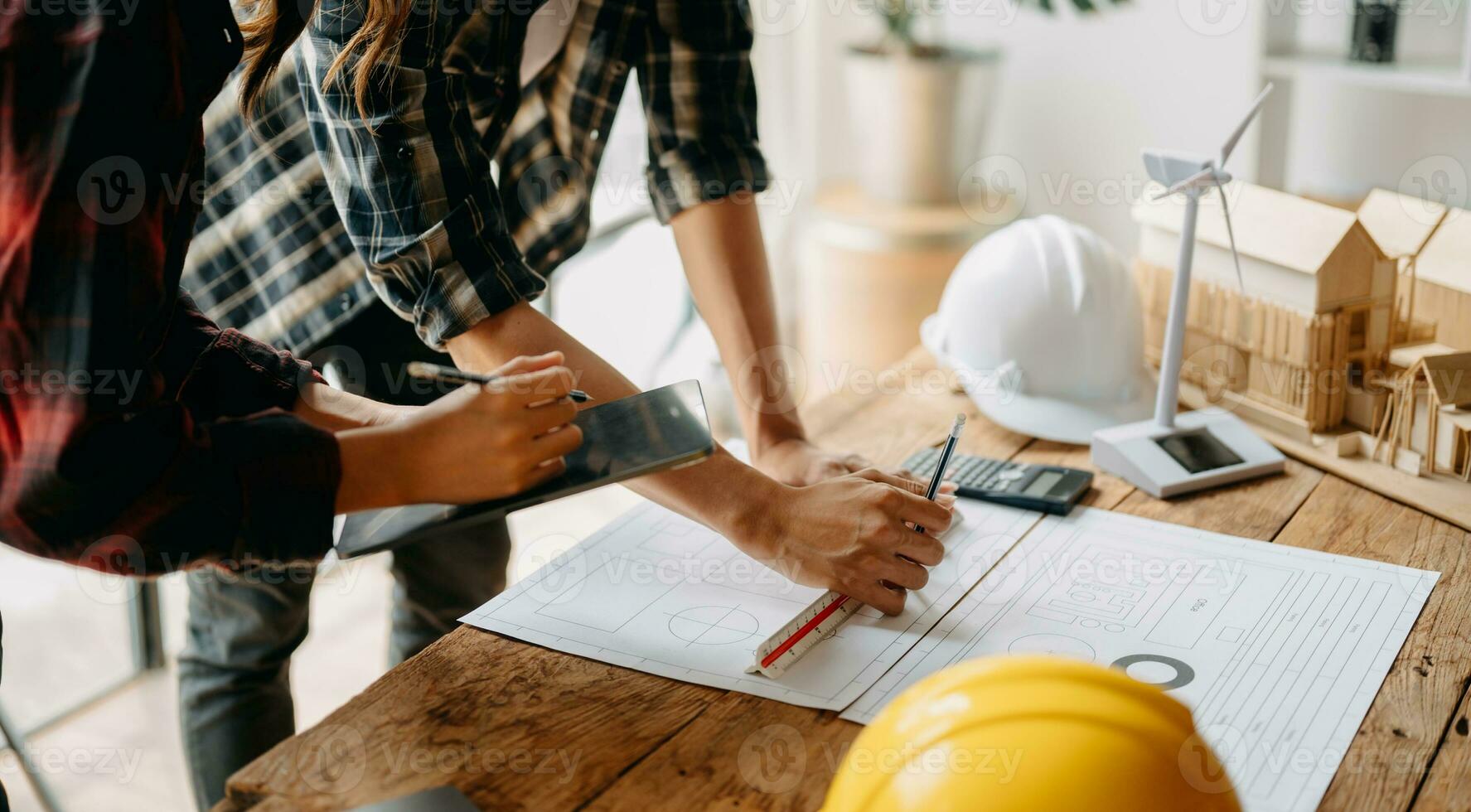 Two colleagues discussing data working and tablet, laptop with on on architectural project at construction site at desk in office photo