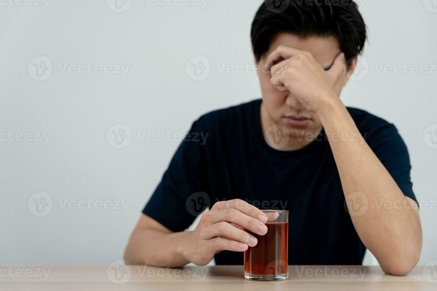 Depressed young Asian man addicted feeling bad drinking whiskey alone at home, stressed frustrated lonely drinking alcohol suffers from problematic liquor, alcoholism, life and family problems photo