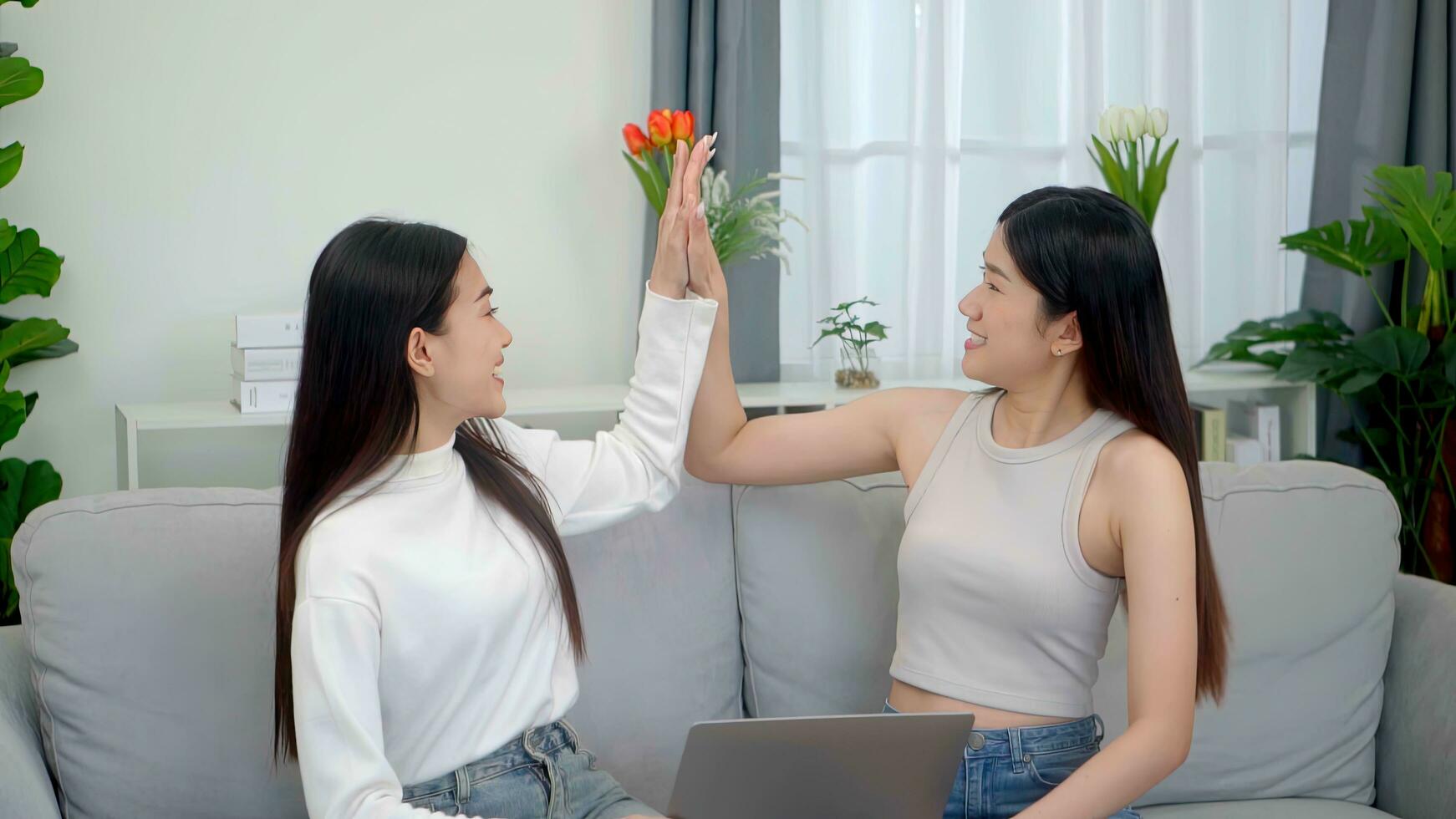 Teamwork happy asian women best friends laughing while working with laptop at home. photo