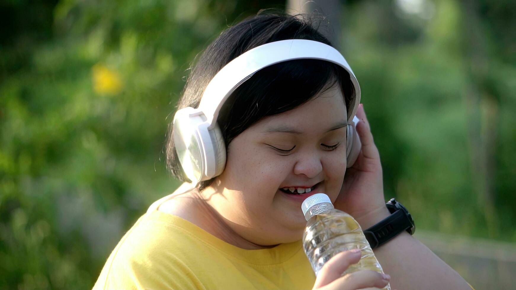 While exercising in the park, an Asian girl with down syndrome uses a water bottle as a microphone. photo