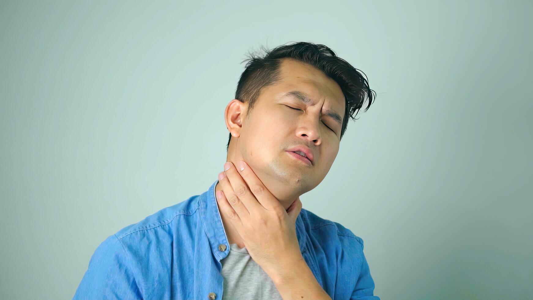enfermo asiático hombre con dolorido garganta en blanco antecedentes foto