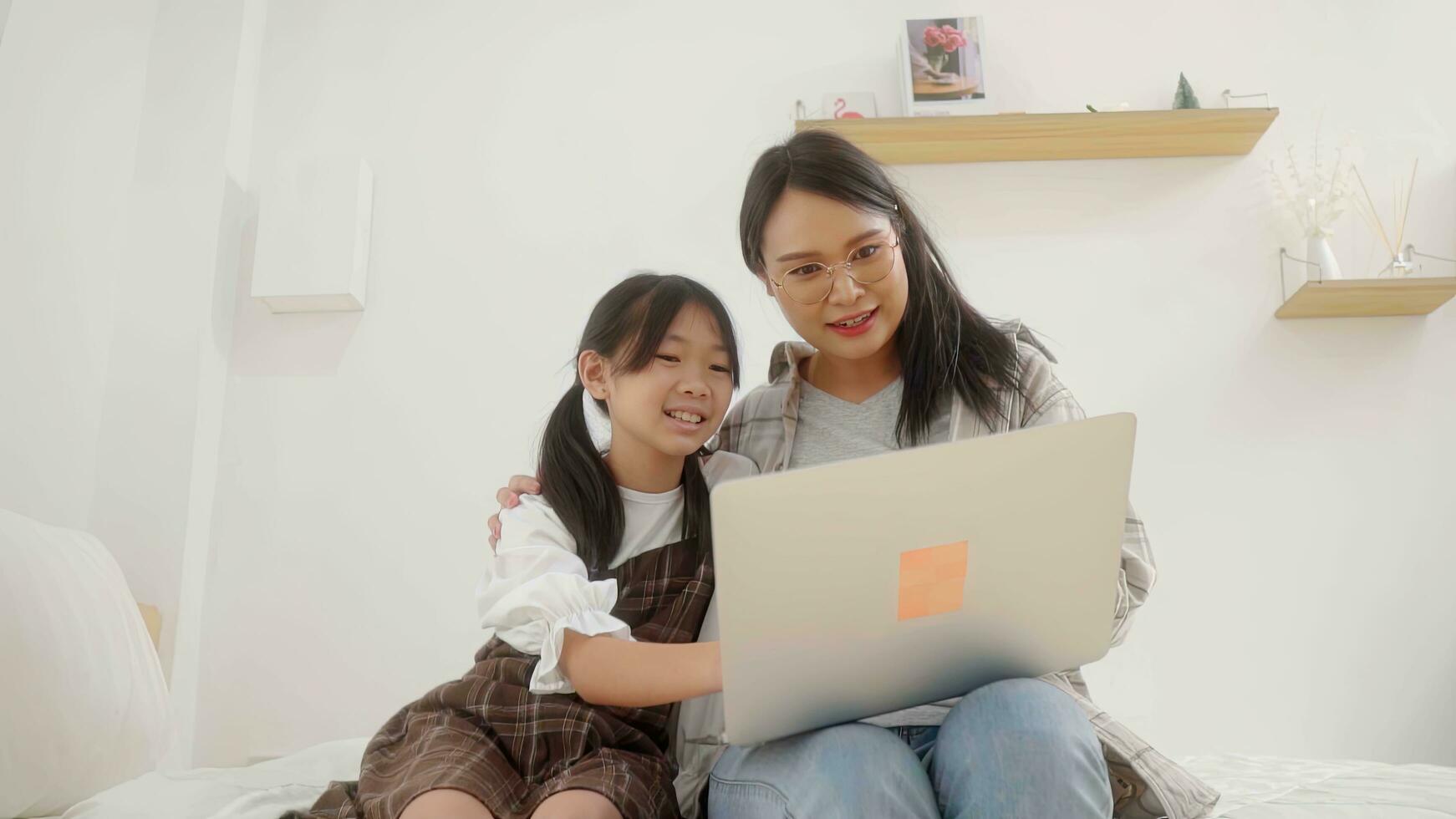 Asian little young girl learning online class at home with mother. photo