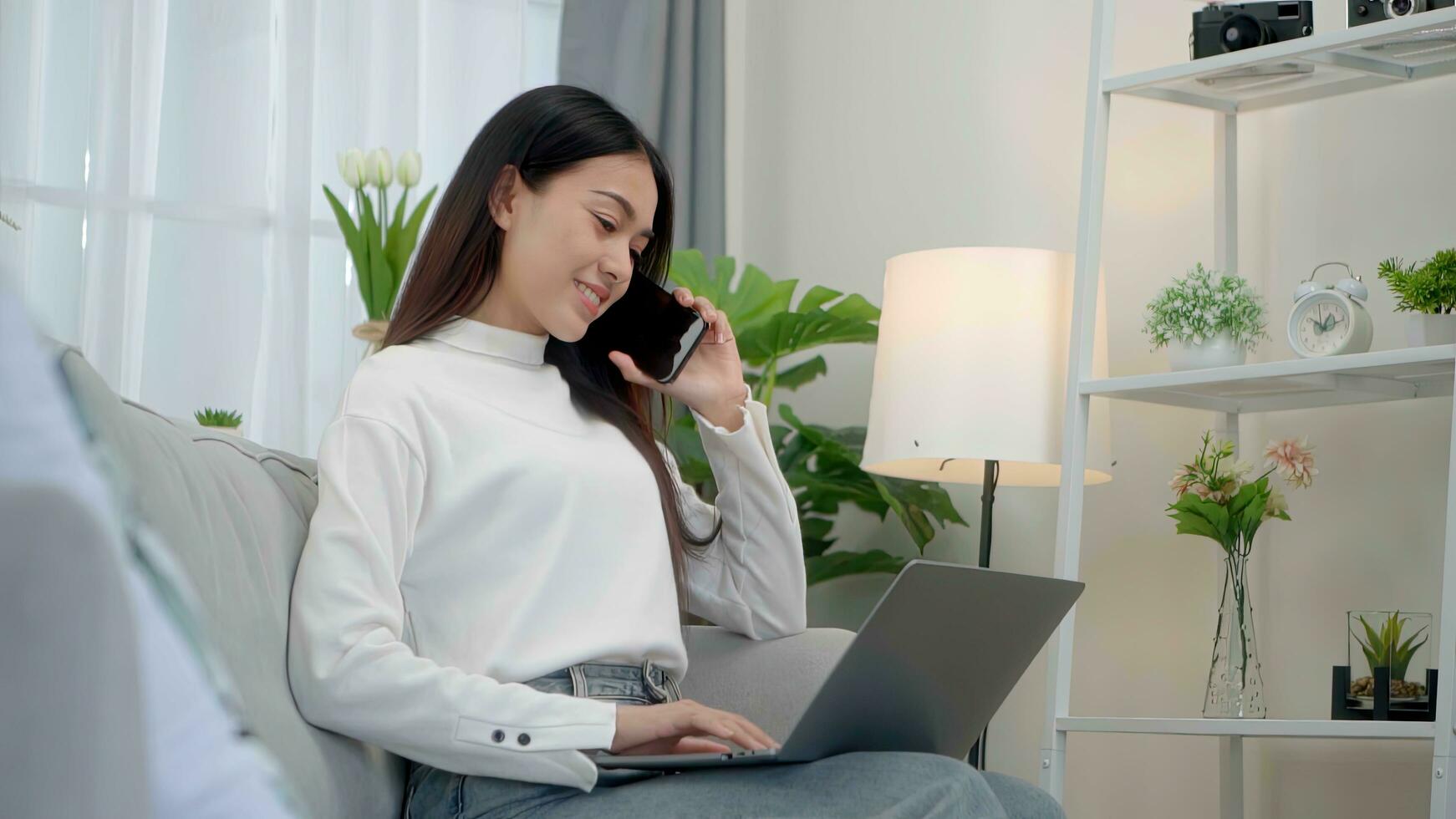 Smiling face asian woman making phone call, working on laptop at home. photo