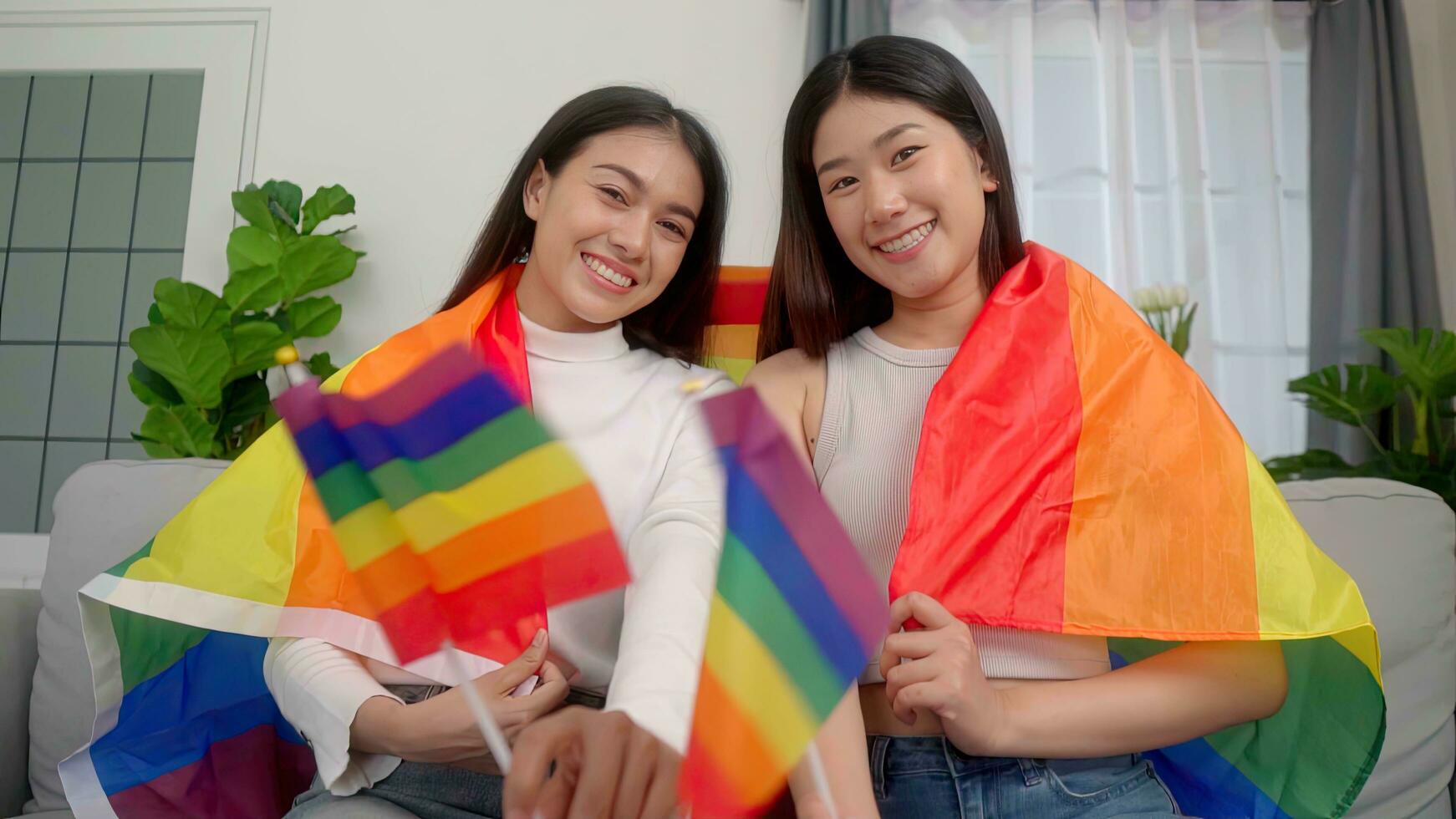 asiático joven hermosa bonito hembra lesbiana sentado abajo y sofá bandera ondulación arco iris igualdad libertad lgbtq gay orgulloso orgullo. foto
