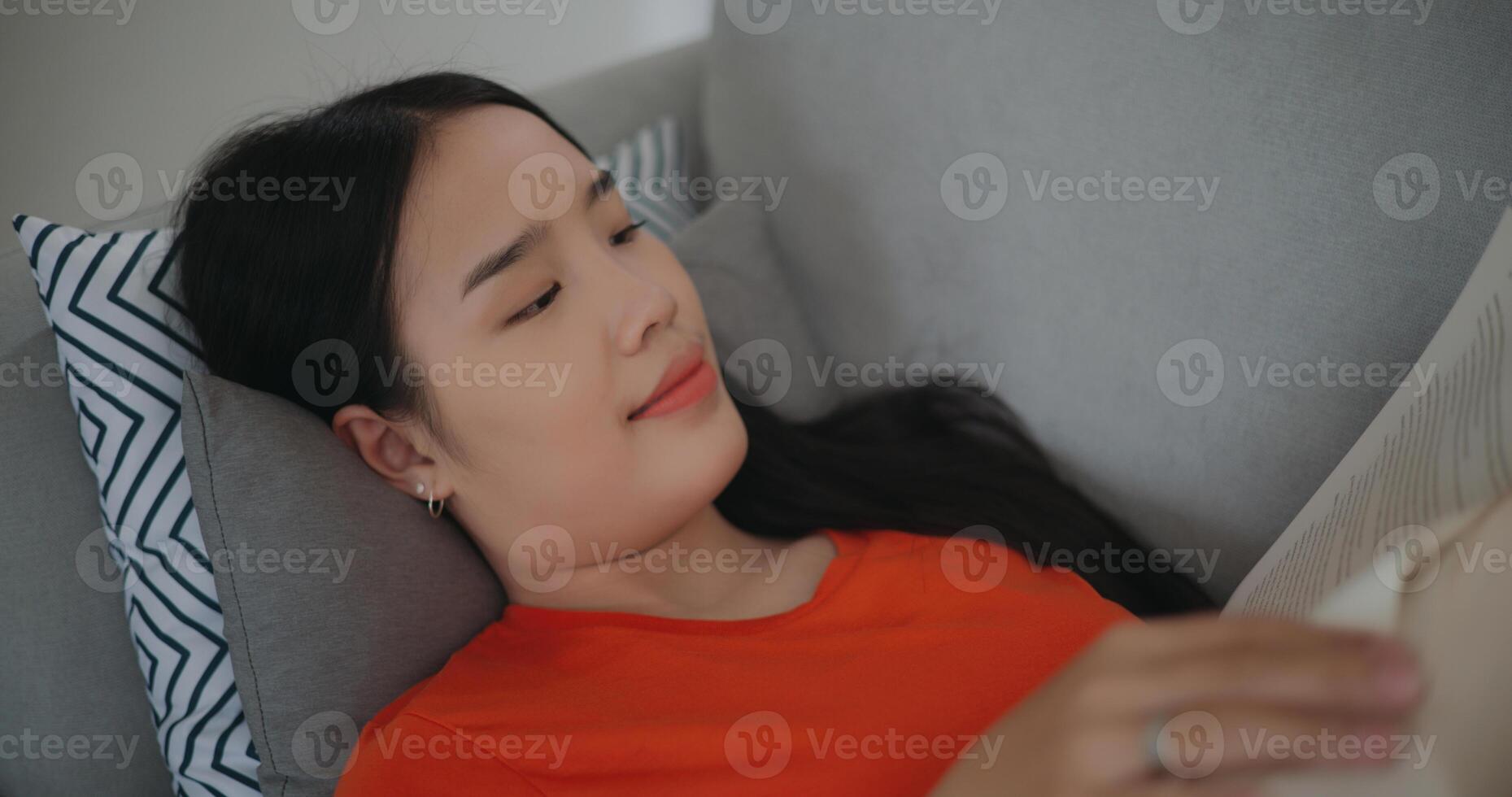 Asian woman reading a book while lying on the sofa photo