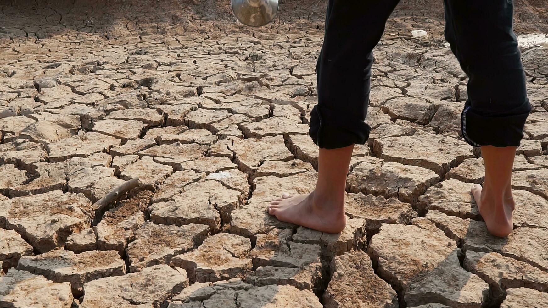 A girl's walking on dry ground. Water crisis, Concept drought and crisis environment. photo