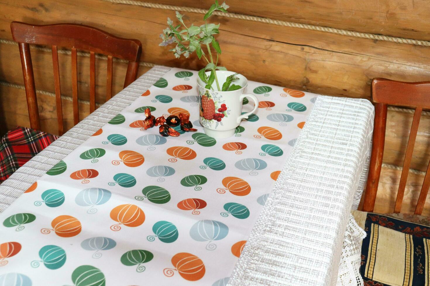 table with tablecloth and kitchen path, wooden retro chairs in rustic house - dining nook in vintage style - horizontal photo