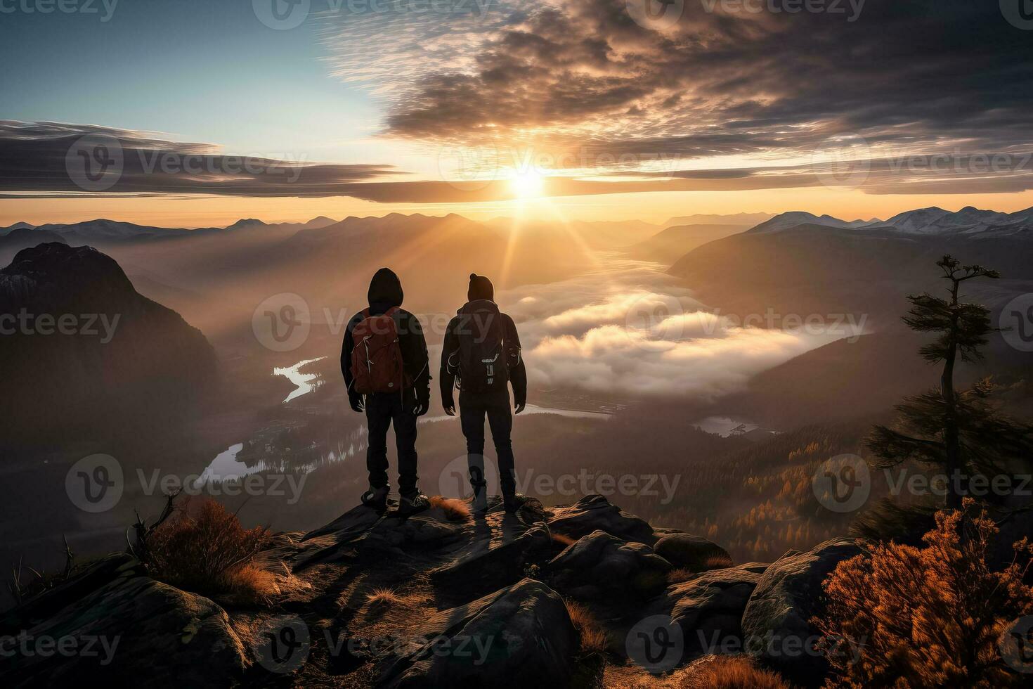 Two hikers support each other on top of a mountain during a beautiful sunrise landscape photo