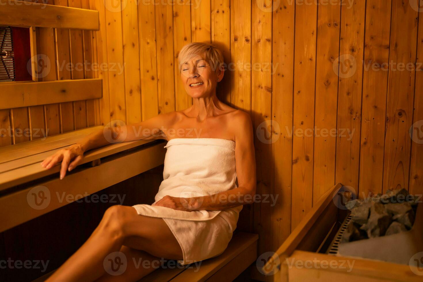 Mature woman is relaxing in sauna. Healthy lifestyle for elderly people. Spa concept. photo