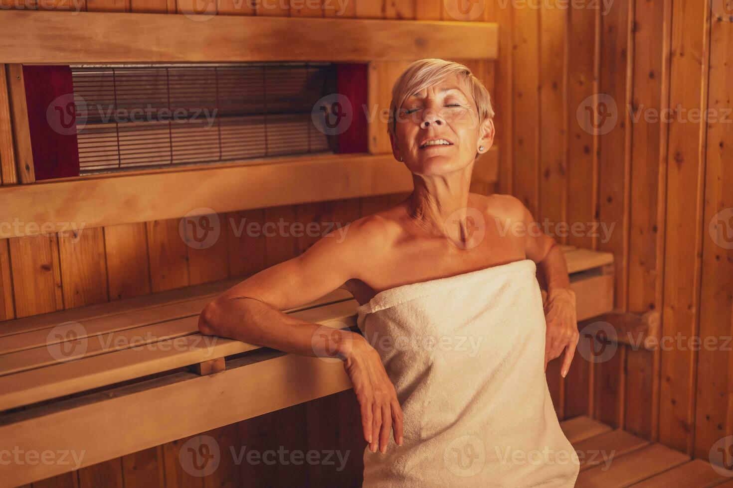 Mature woman is relaxing in sauna. Healthy lifestyle for elderly people. Spa concept. photo