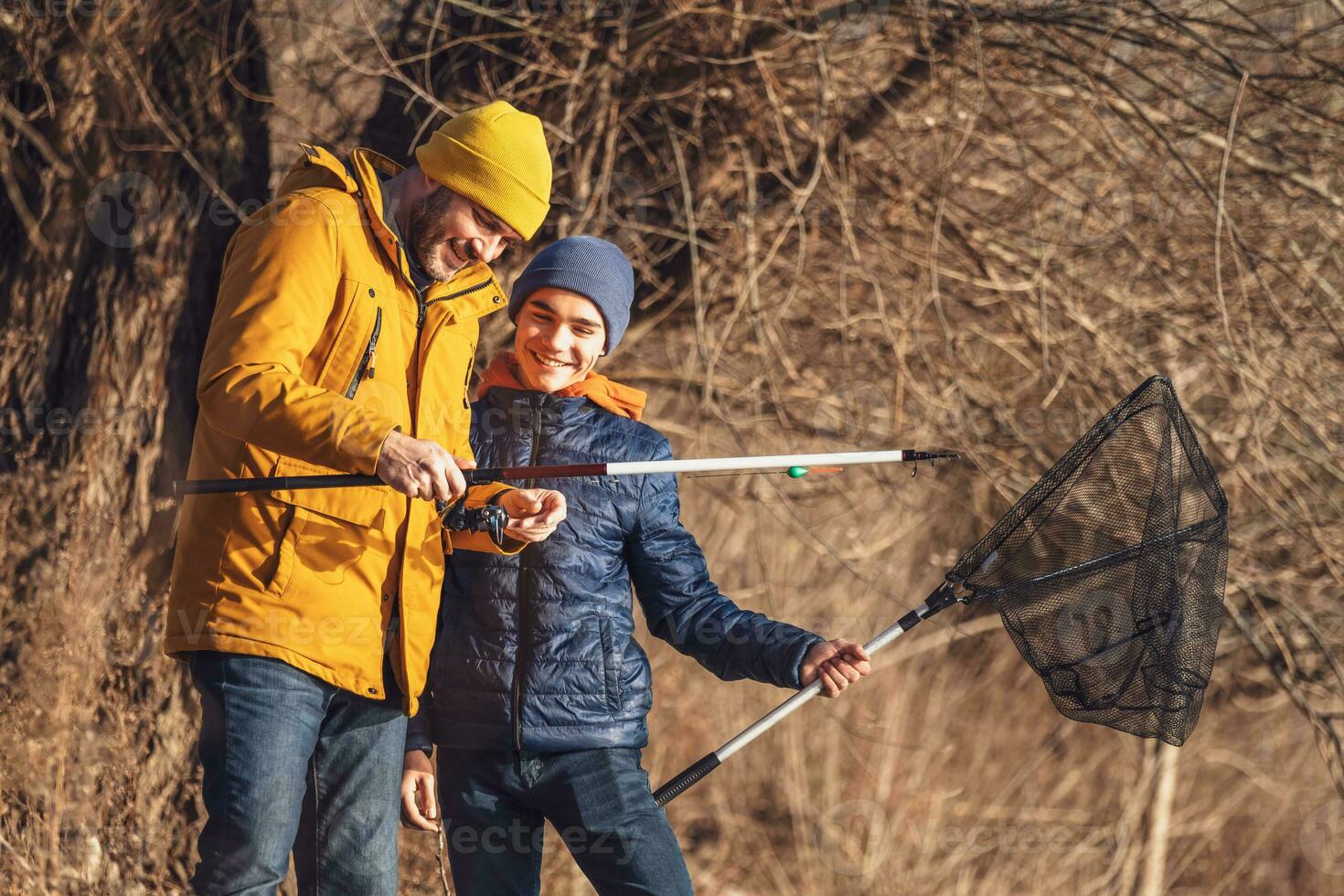 Father and son are fishing on sunny winter day. Freshwater fishing