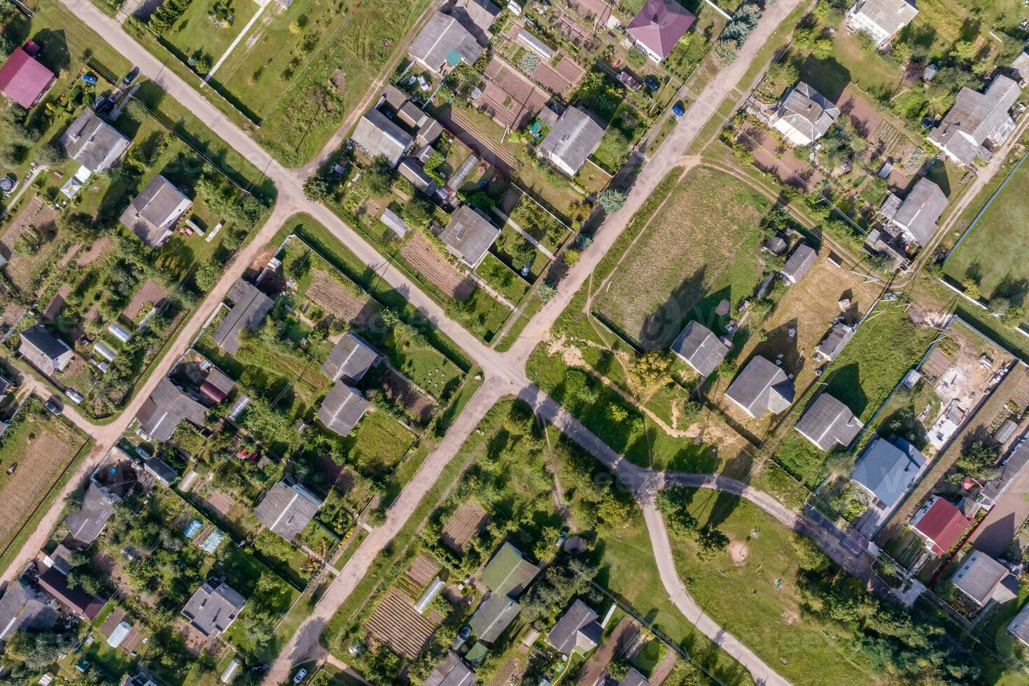 panoramic aerial view of eco village with wooden houses, gravel road, gardens and orchards photo