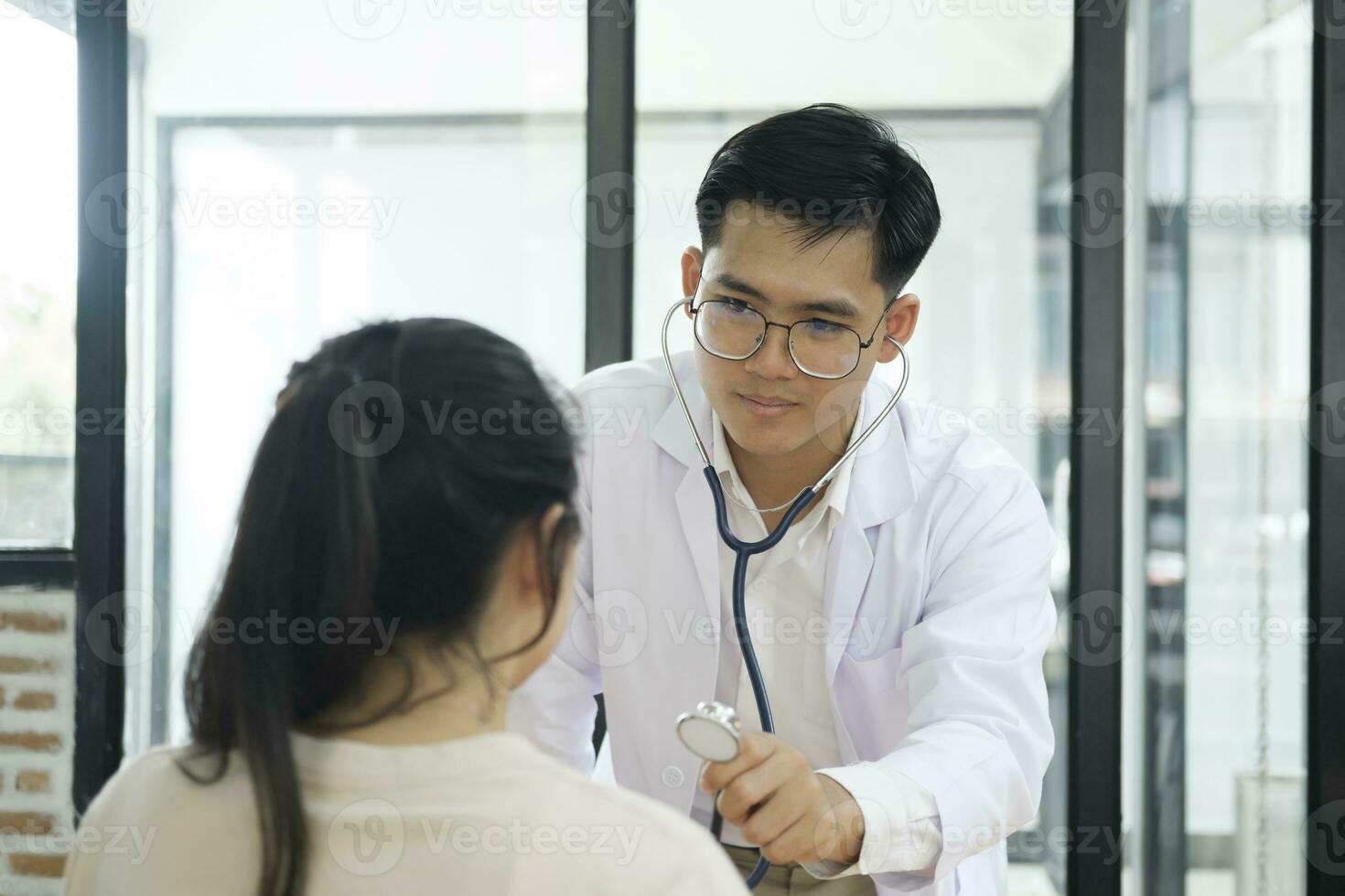 joven médico es utilizando un estetoscopio escucha a el latido del corazón de el paciente. foto