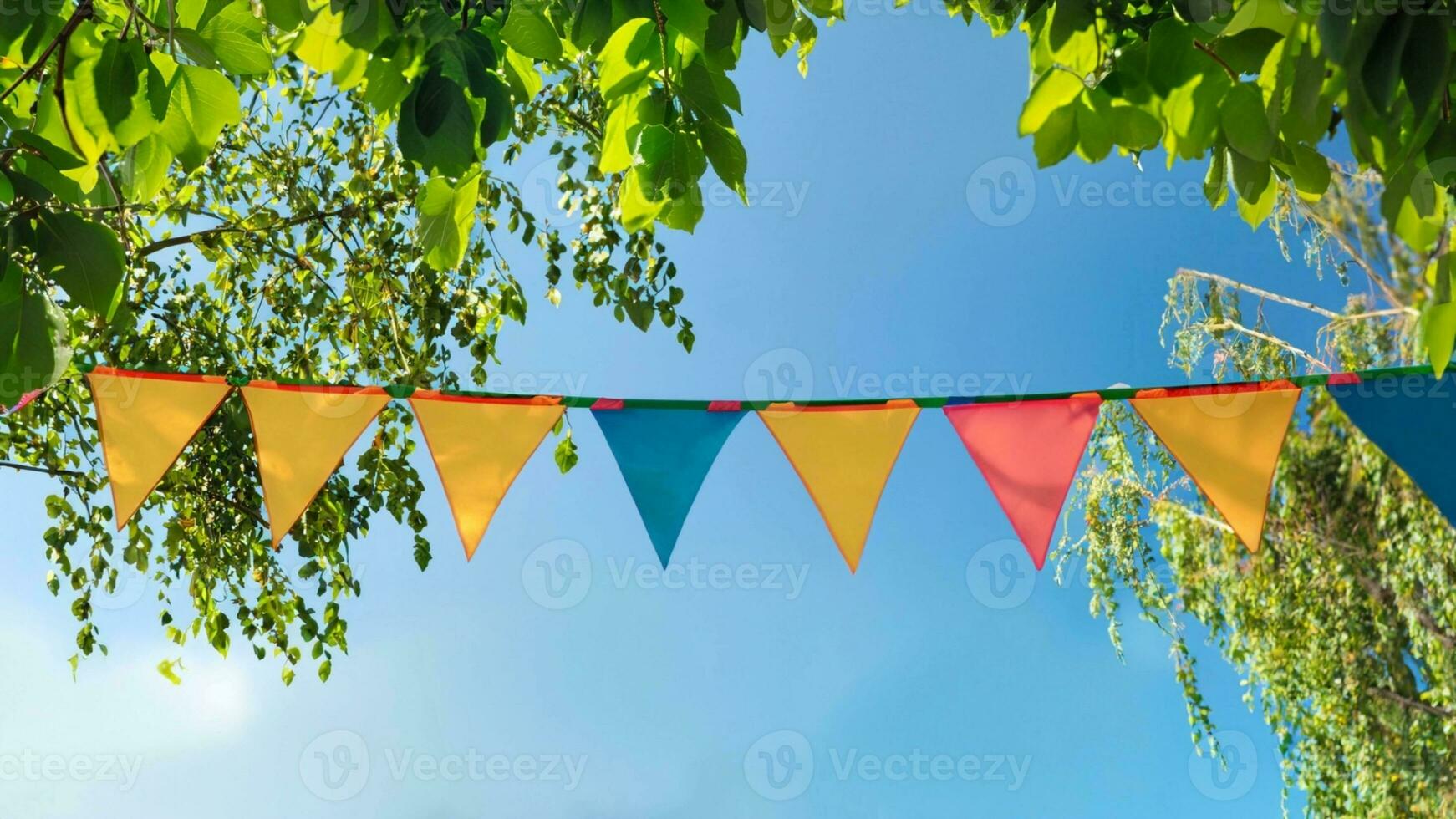 colorful pennant string decoration in green tree foliage on blue sky, summer party background photo