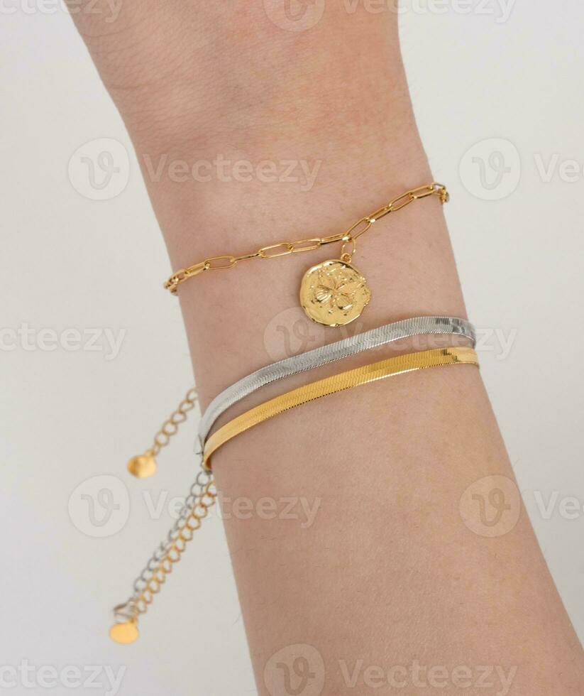 Woman wrist wearing golden butterfly and snake chain bracelets set against a white background.  Beautiful valentine's gift. photo