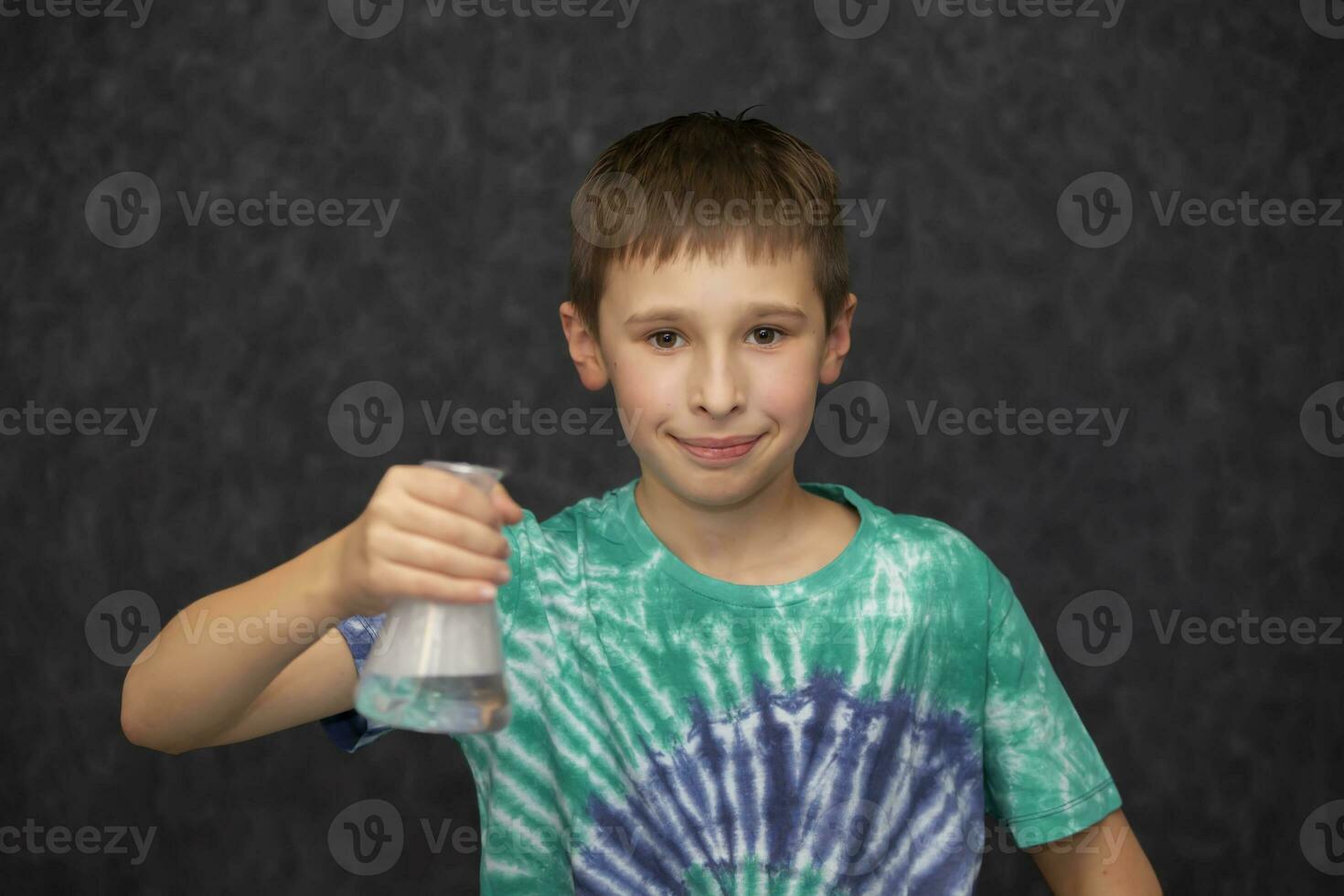 The boy holds a glass chemical flask in his hand. photo