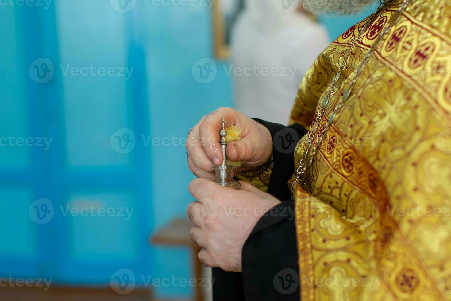 The hands of an Orthodox priest hold a bottle of myrrh oil for the rite of baptism. photo