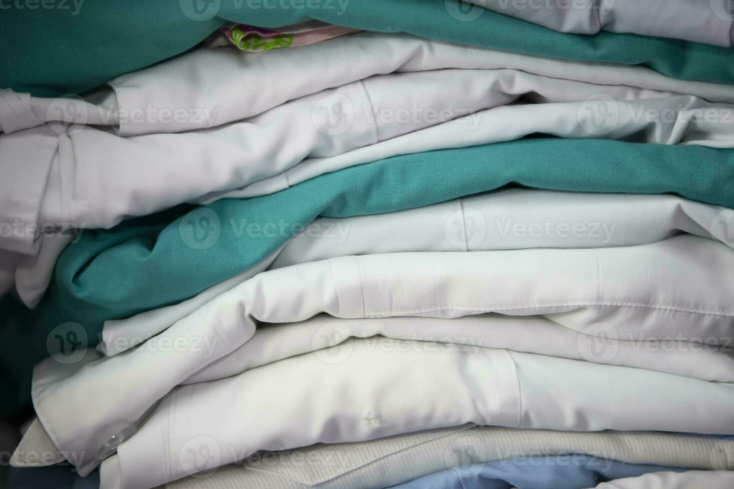 White and green medical gowns are stacked. photo