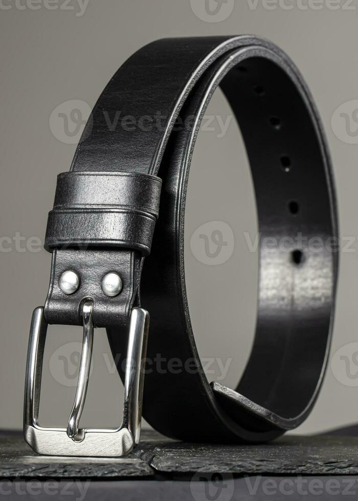 Leather belt twisted into a circle on a gray background. photo