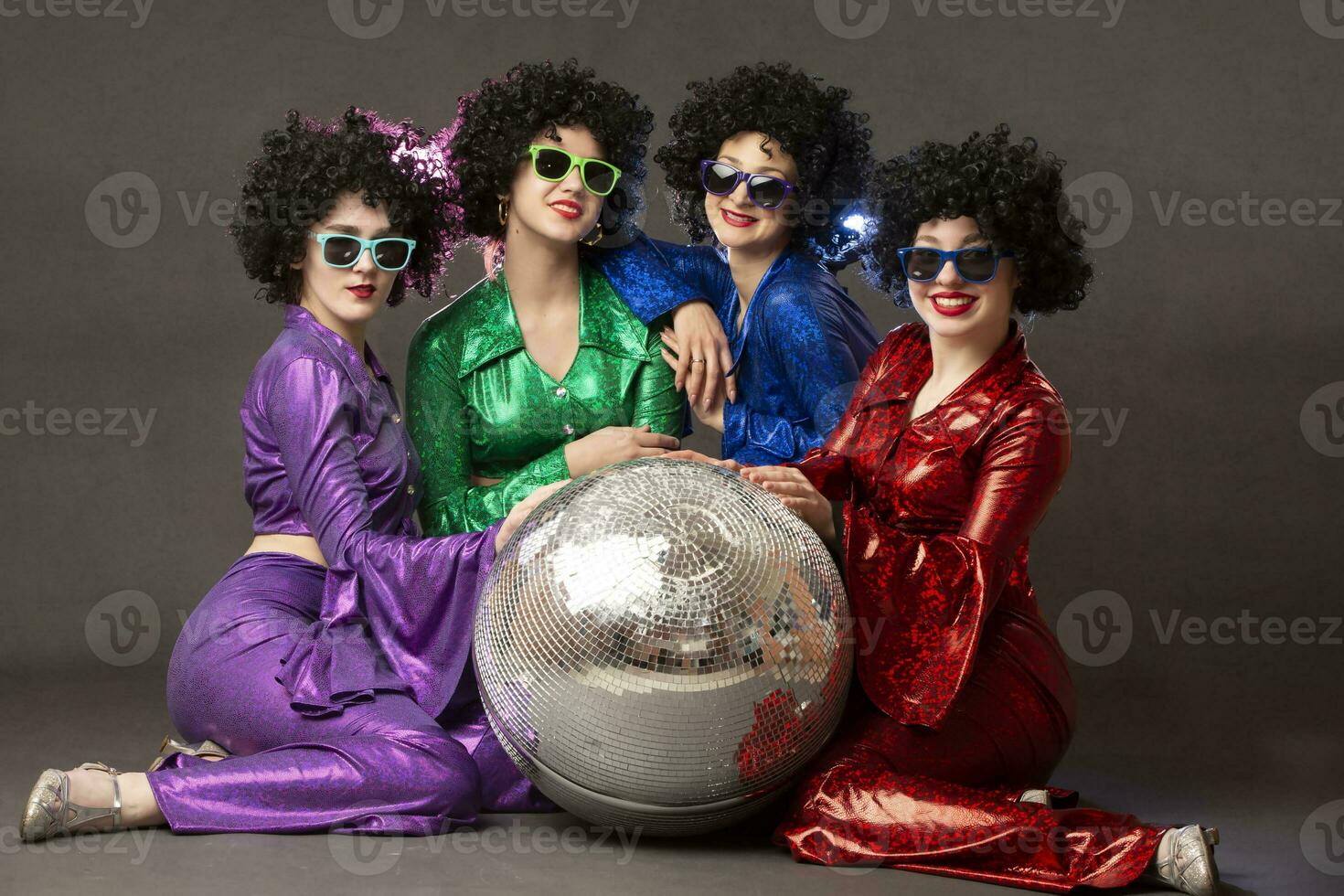 Group of happy girls in disco style, with disco ball, halloween party, on gray background. 80s themed party. photo