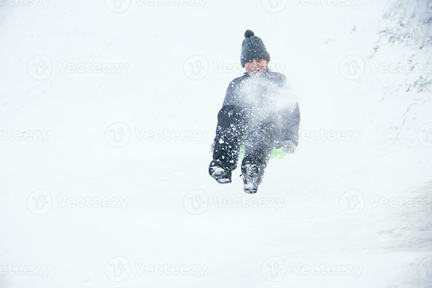 Child sledding cheesecake.Sledding off a snow slide photo