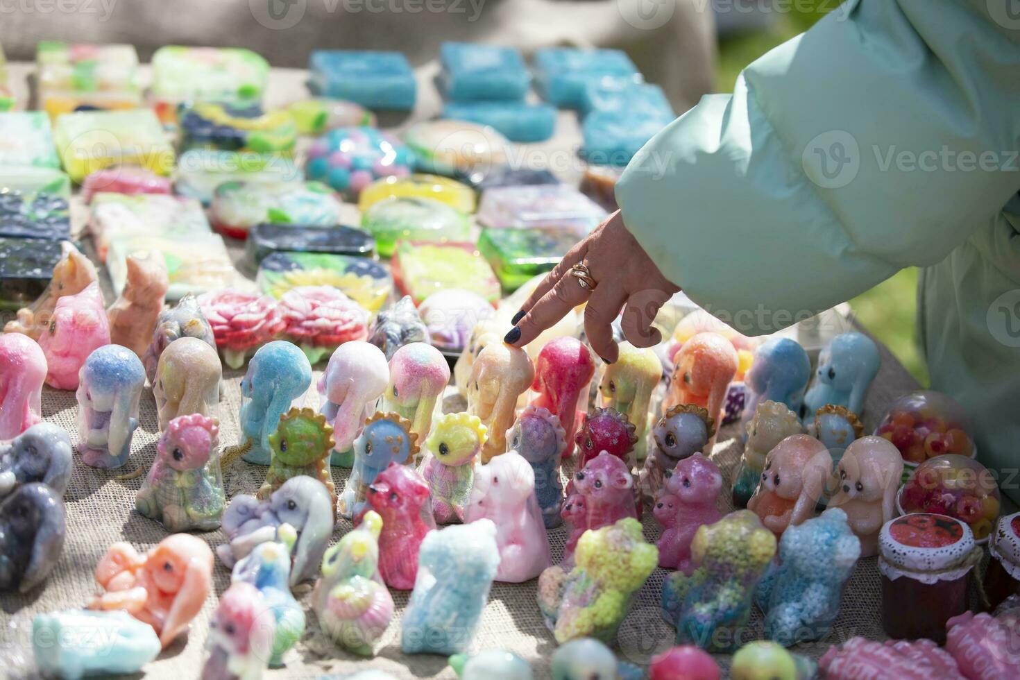 Sale at the fair of handmade soap. The buyer's hand points to the product he likes. photo