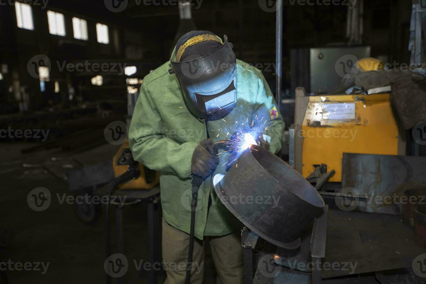 Welder at work. Man in a protective mask. The welder makes seams on the metal. Sparks and smoke when welding. photo