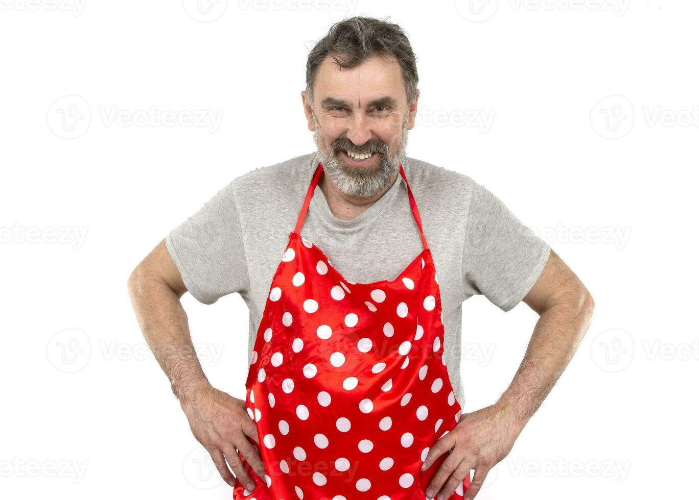 An elderly bearded man in a red polka-dot culinary apron on a white background. photo