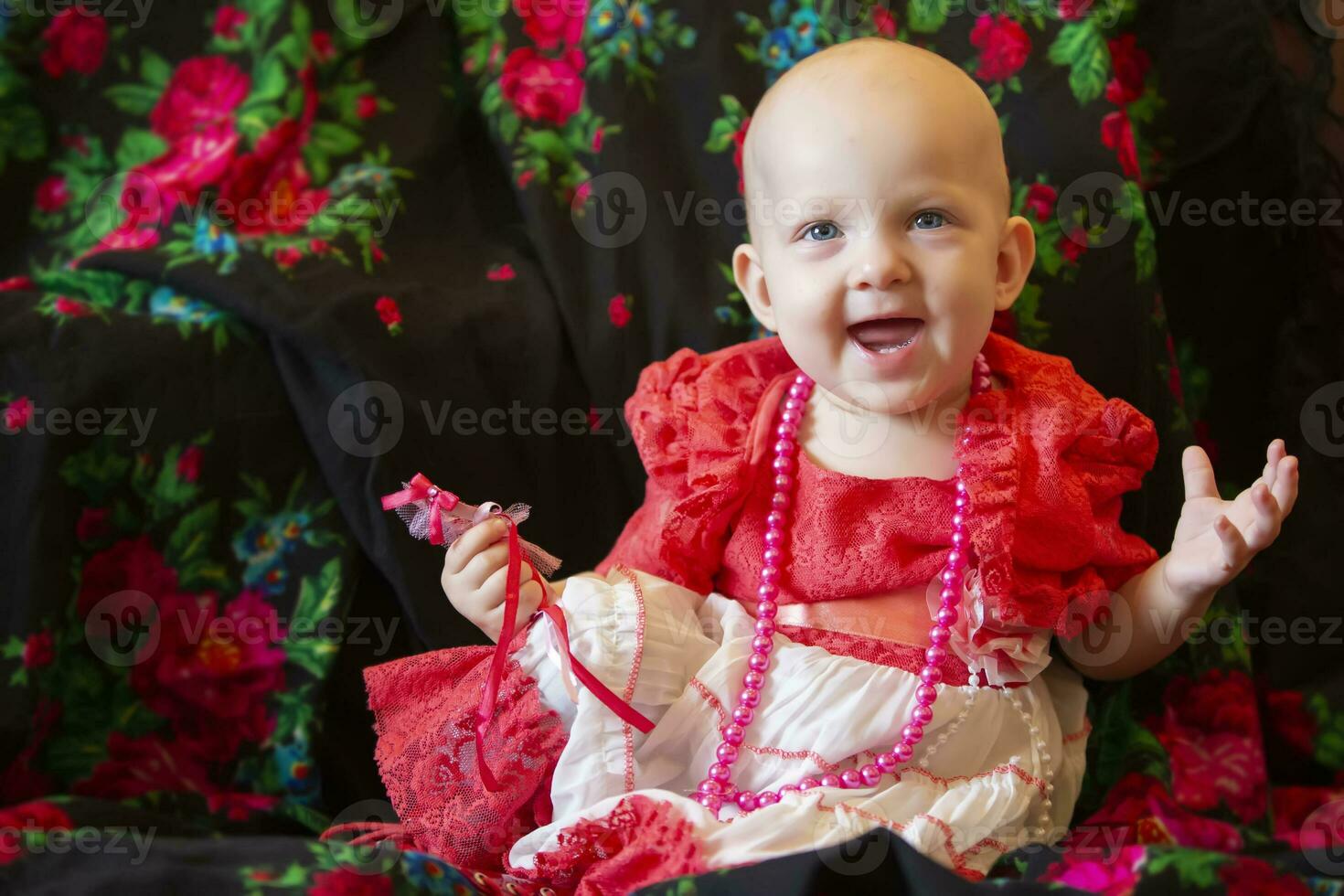 Funny little girl under one year old with beads smiles and looks at the camera. Little fashion-girl. photo