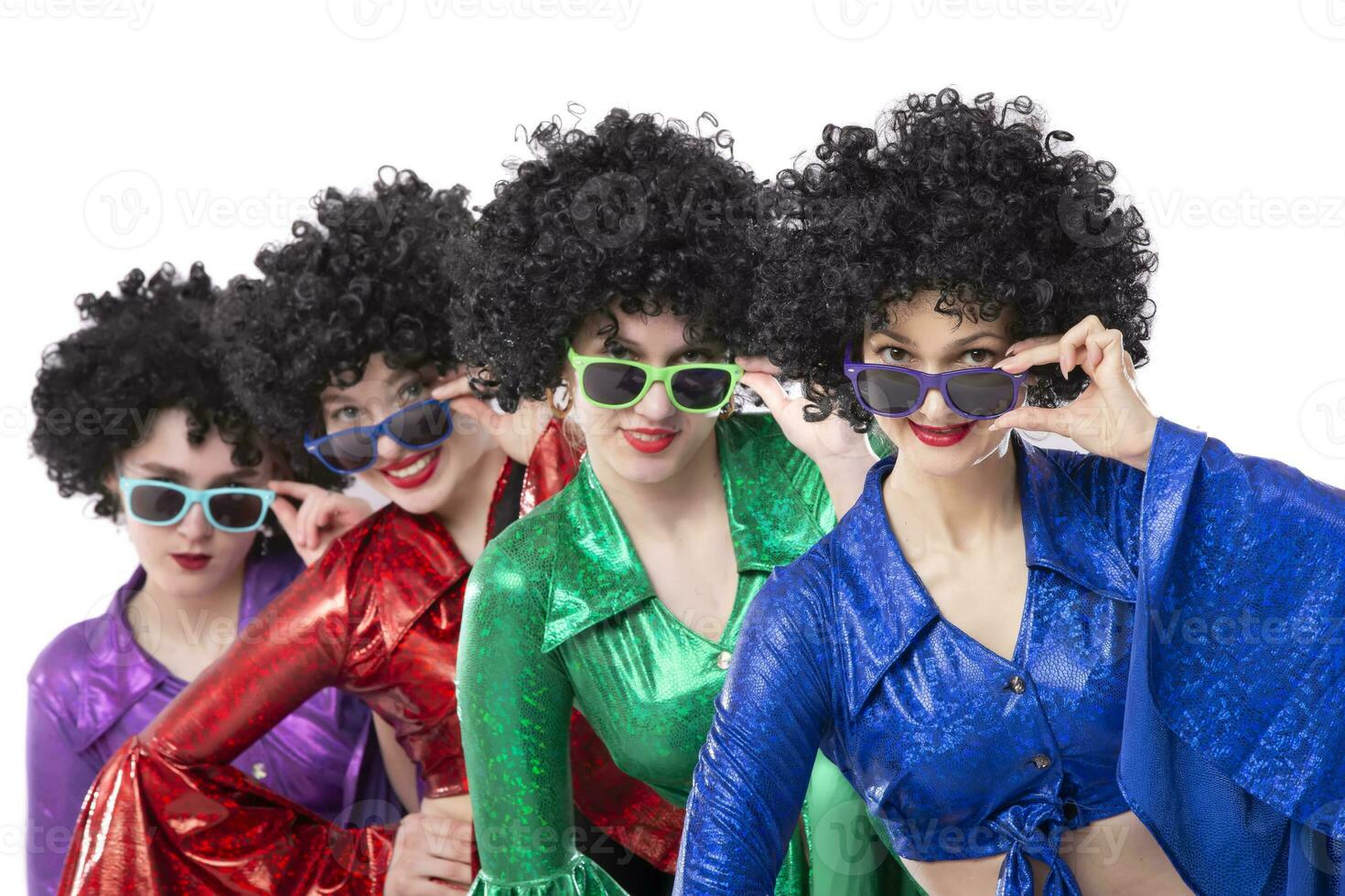 A group of girls in disco style and African wigs in colorful costumes on a white background. photo