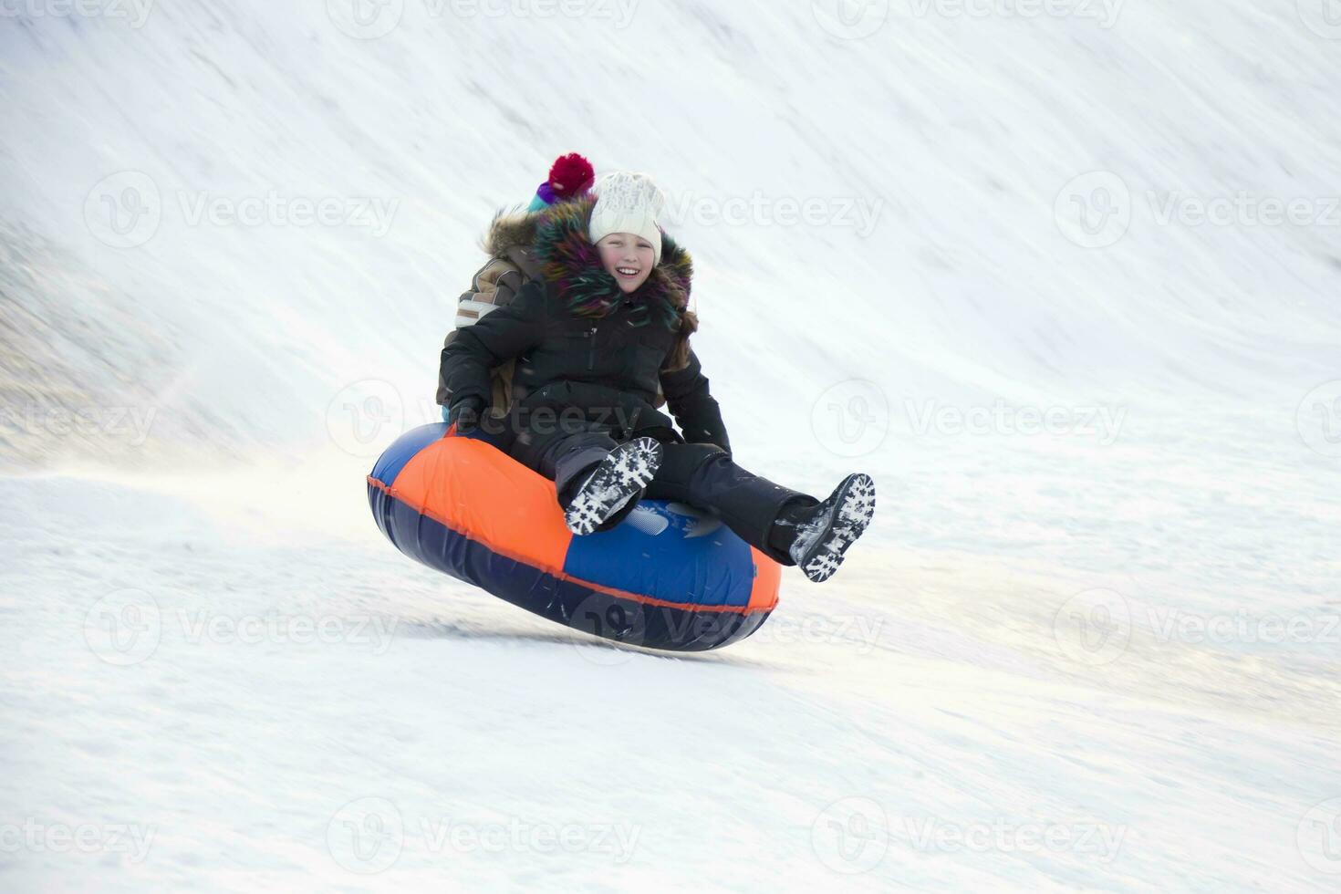 .Child sledding cheesecake.Sledding off a snow slide photo