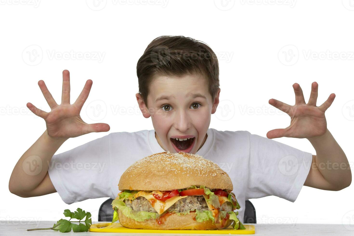 Young eccentric boy with a big hamburger isolated in white. The teenager shows a good appetite. photo