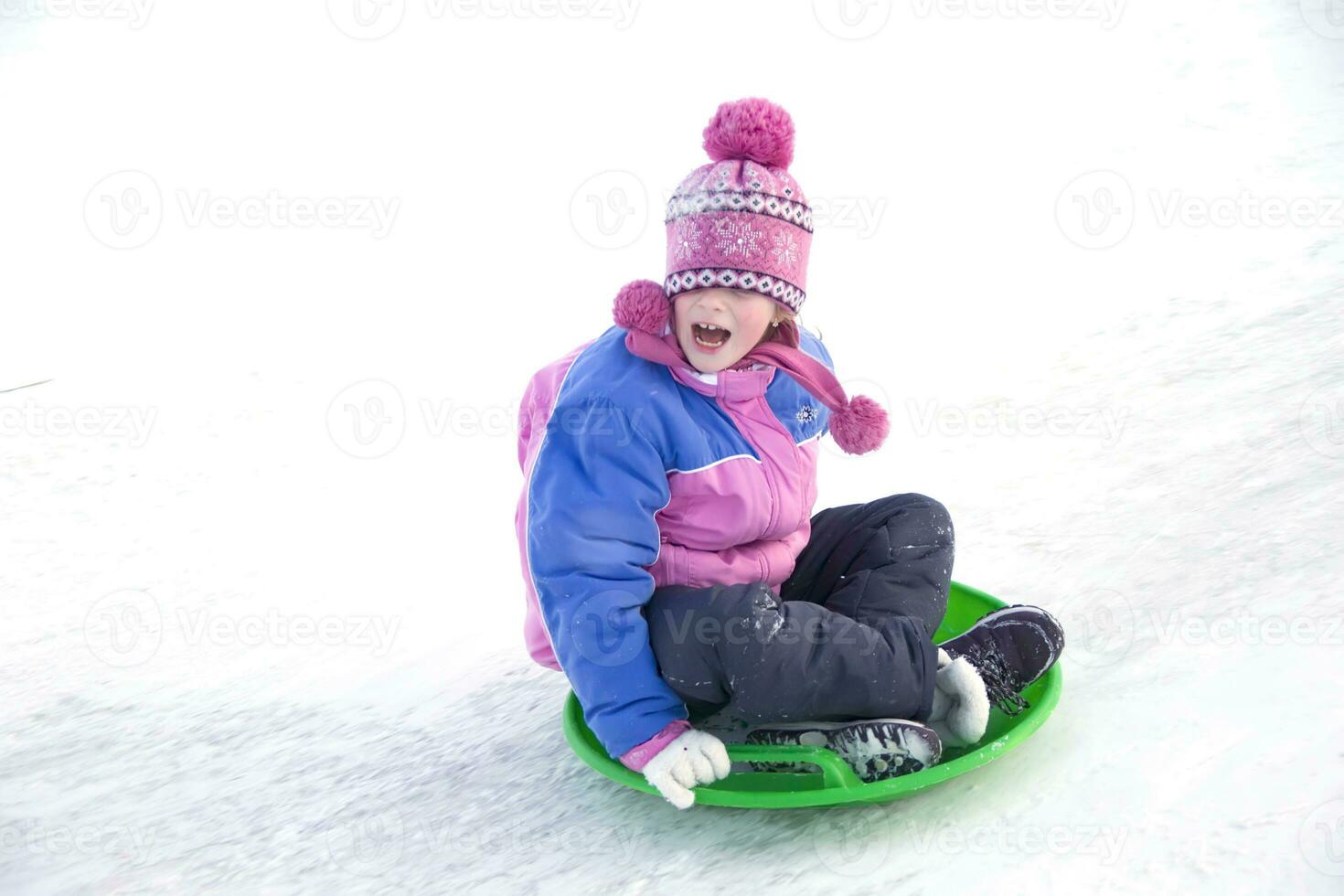 A girl in a winter jacket screaming moves down from a snow slide photo