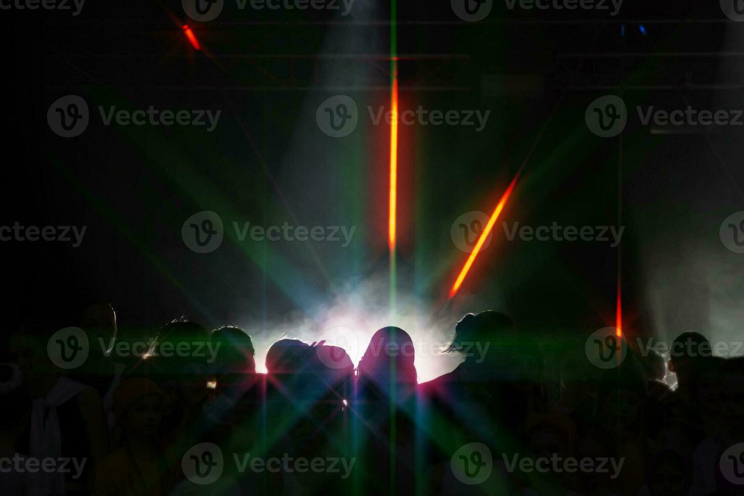 Dark silhouettes of dancing people and a beam of light in a nightclub. photo