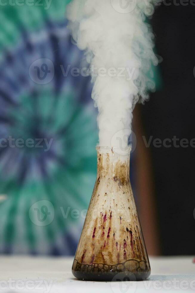 In a chemical flask, a substance reacts and smoke comes out. photo