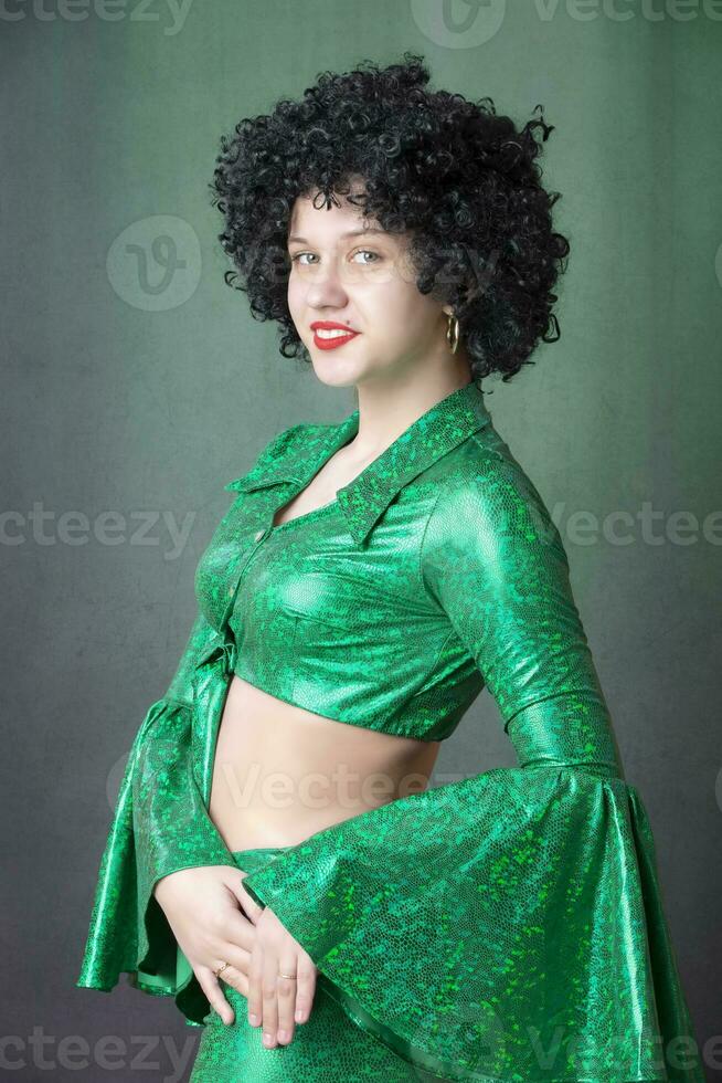 Beautiful vintage woman in an afro wig on a gray background. Disco girl. photo