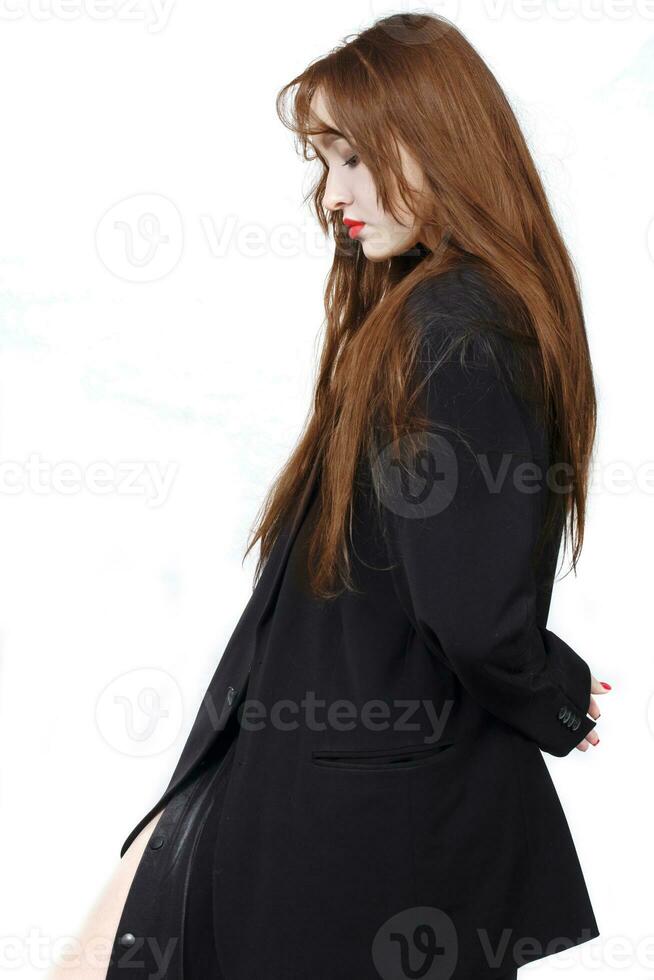 Portrait in profile of a beautiful girl with red long hair in a black jacket on a white background. photo