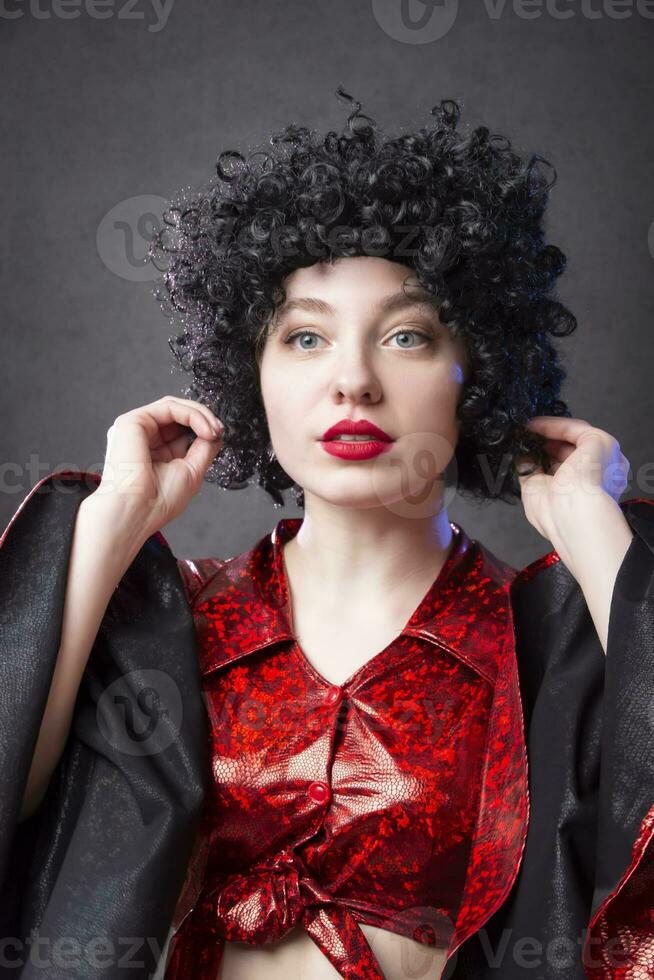 Funny vintage woman in an afro wig on a gray background. Disco girl. photo
