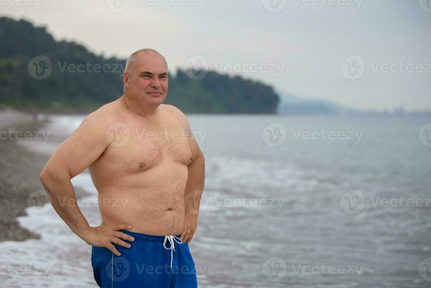 An elderly man of athletic build on the background of the sea. photo
