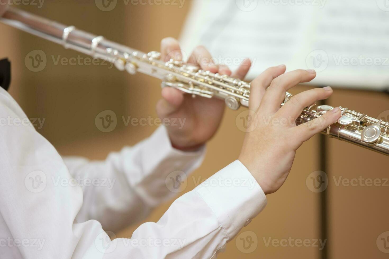 The boy plays the shining flute. Wind musical instrument. photo