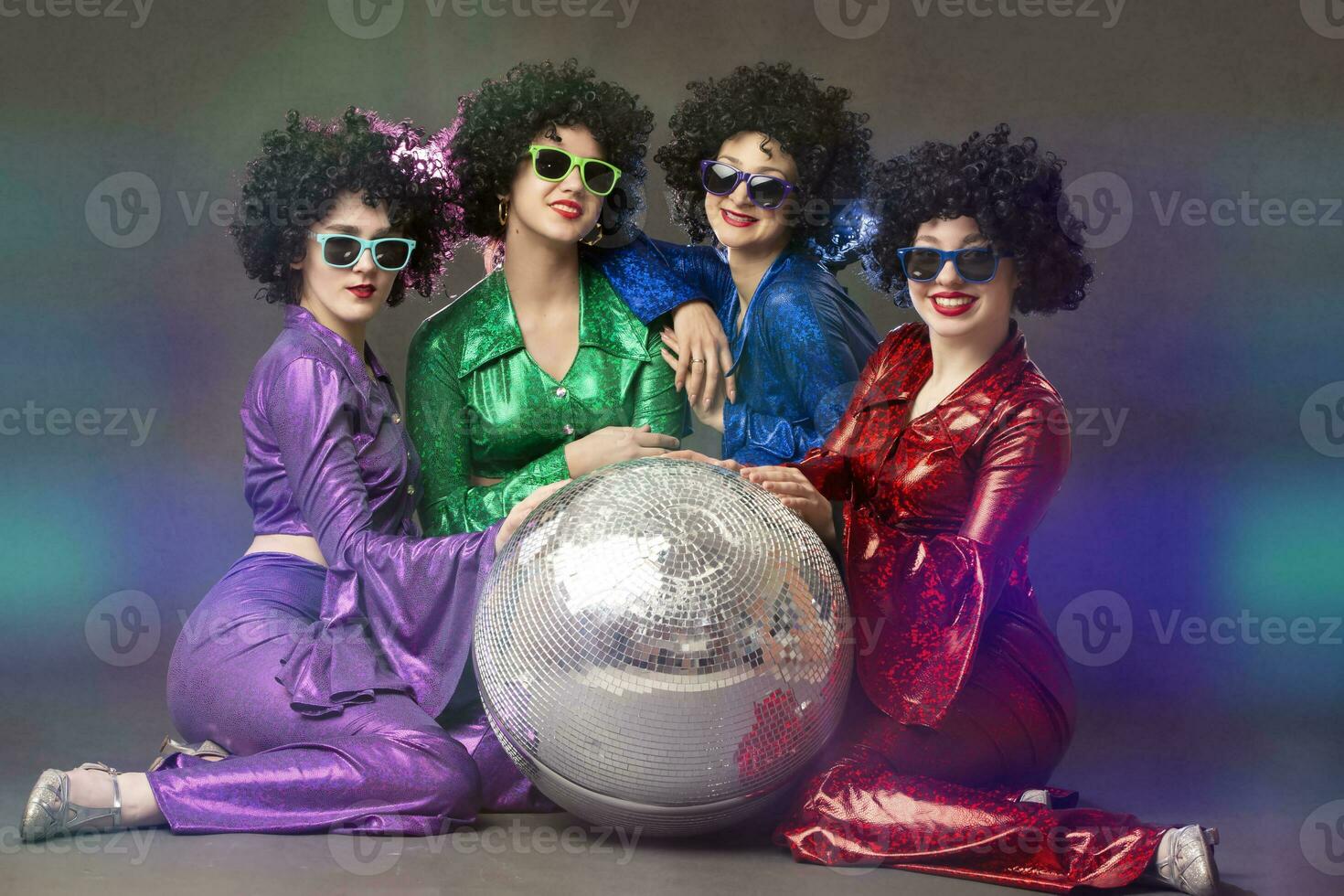 Group of happy girls in disco style, with disco ball, halloween party, on gray background. 80s themed party. photo