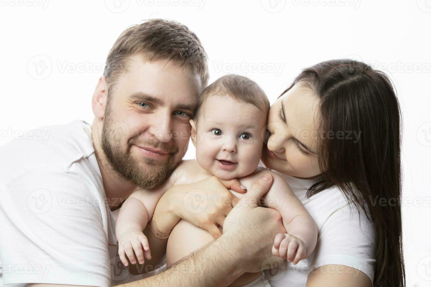 Close up portrait of young parents and baby. Father and mother kiss and hug a beautiful little son. The concept of love, happy fatherhood and motherhood. photo