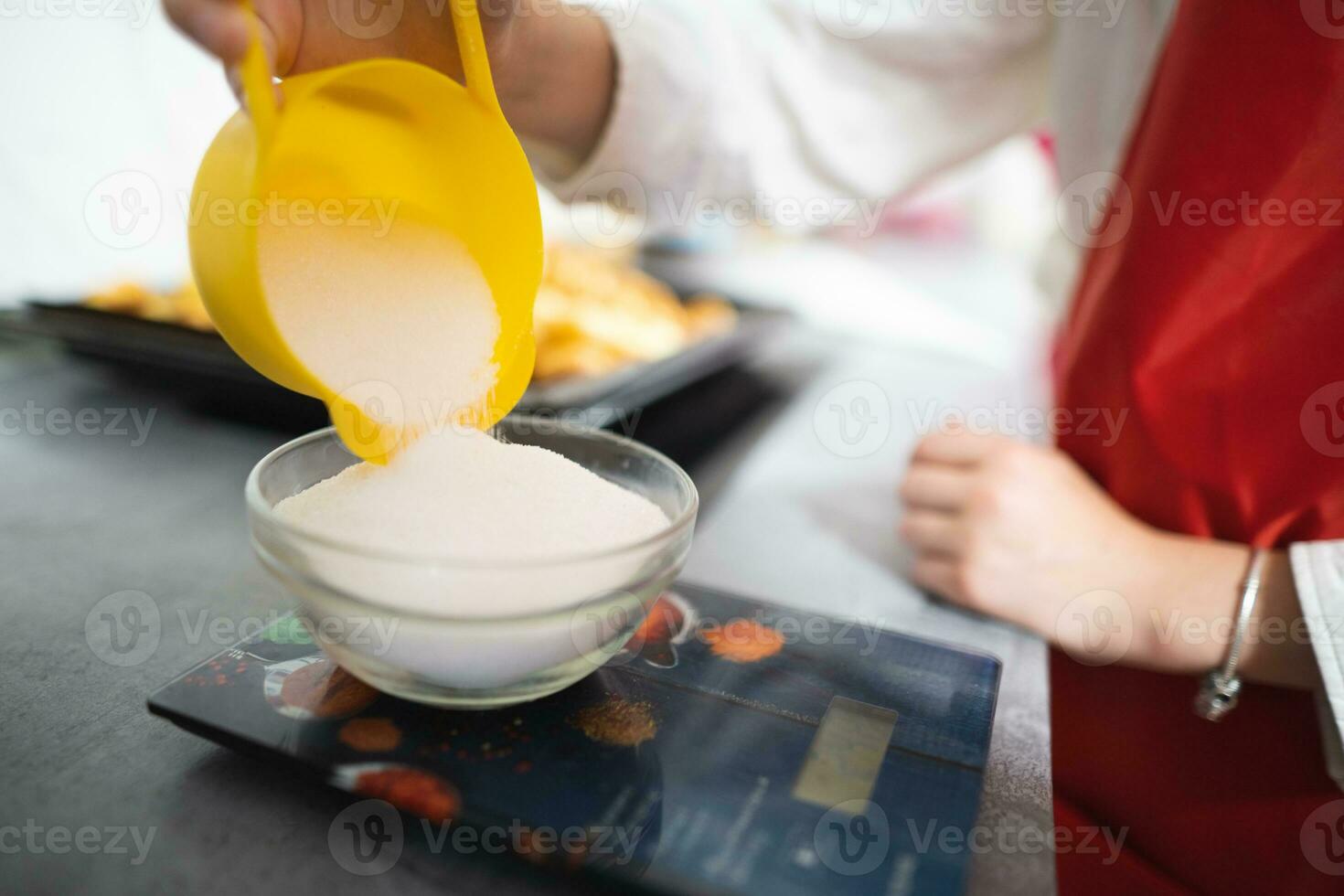 the cook pours sugar into a bowl on the scales photo