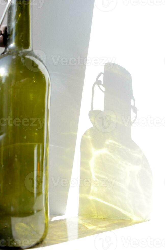 Empty Glass Wine Bottle green shadow on wall. Alcohol beverage Sunlignt reflection. Silhouette on surface. Vertical photography for banner, poster, bar, restaurant, placard, flyer. photo