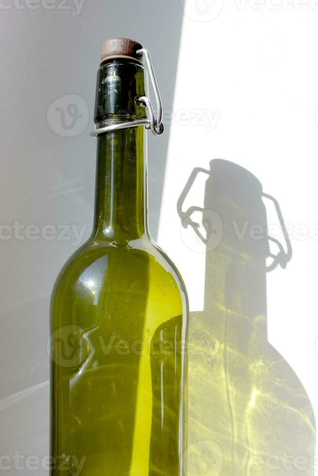 Empty Glass Wine Bottle green shadow on wall. Alcohol beverage Sunlignt reflection. Silhouette on surface. Vertical photography for banner, poster, bar, restaurant, placard, flyer. photo