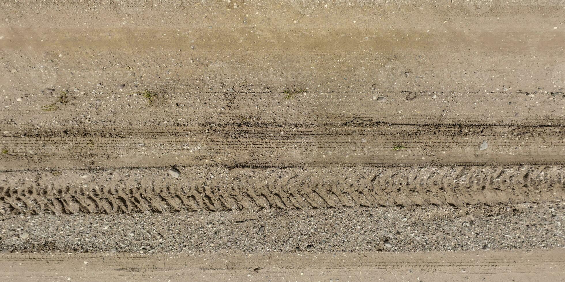 panorama of road from above on surface of gravel road with car tire tracks in countryside photo