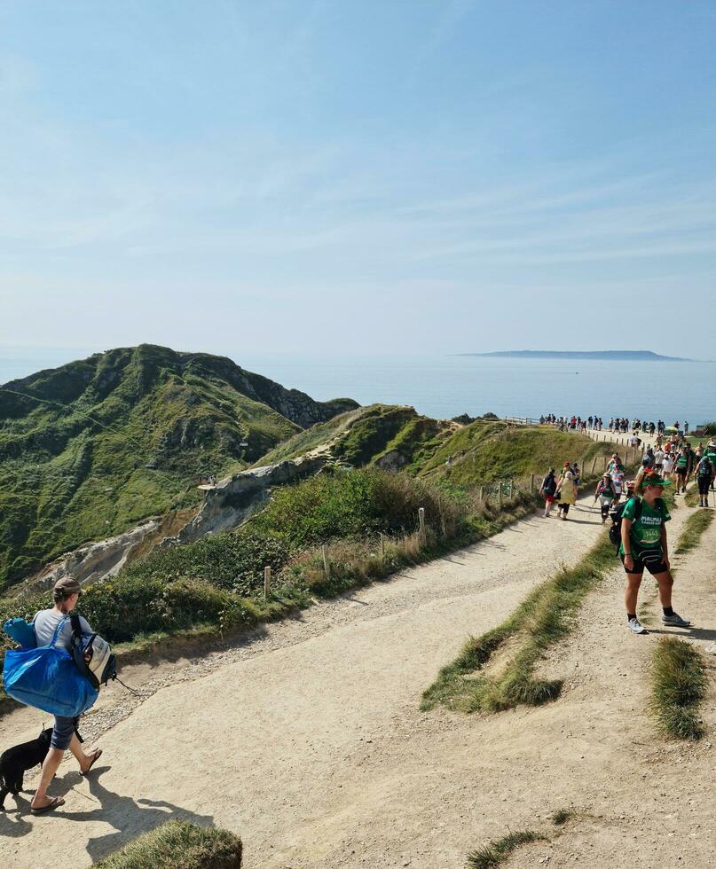 High Angle View of People are Approaching to Durdle Door Beach Which is Most Famous Tourist Attraction Place Through Walking Distance over Landscape and Hills. Captured on September 9th, 2023 photo